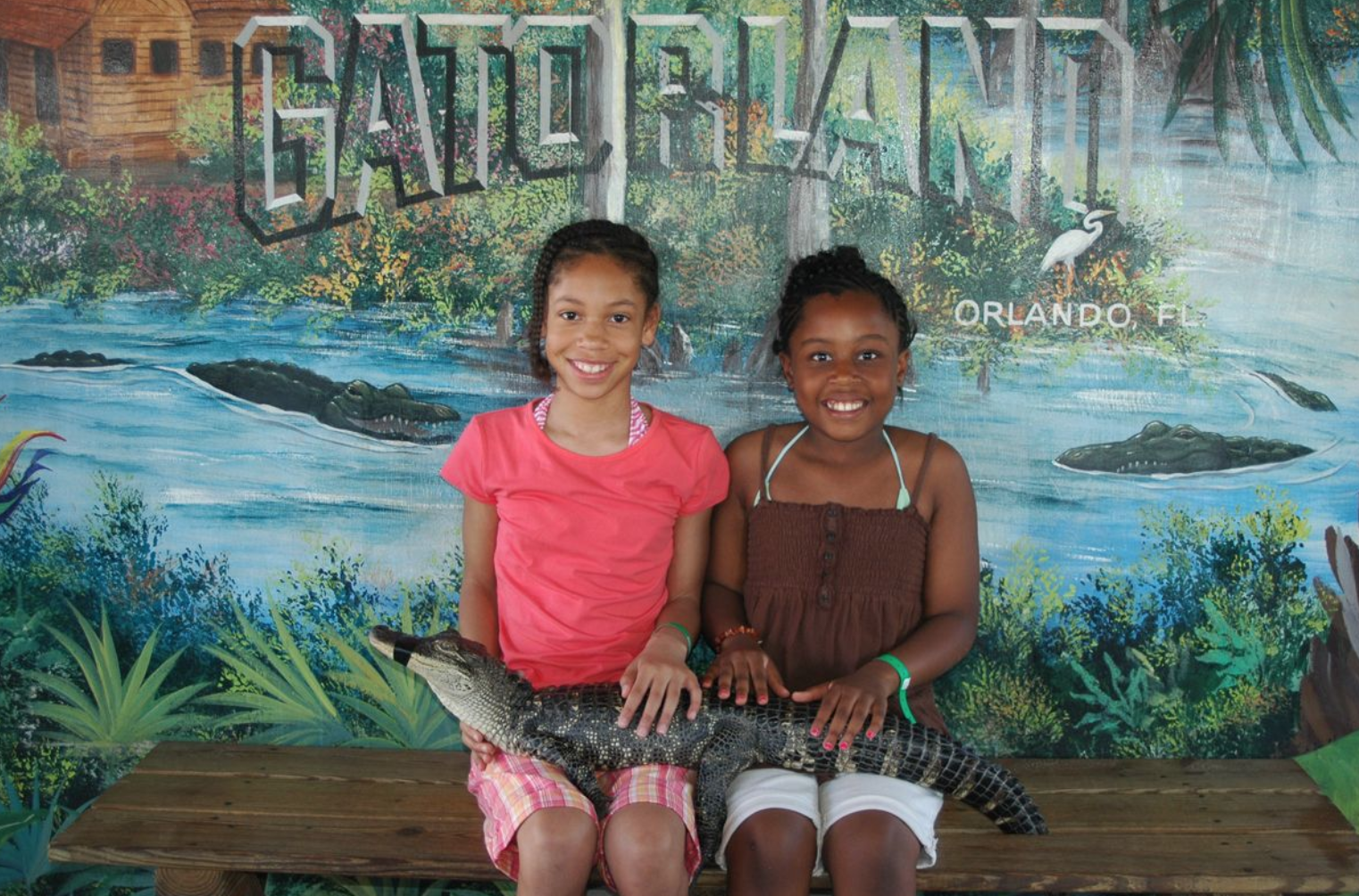 Gatorland Orlando deals: image of two girls holding a baby alligator at Gatorland Orlando theme park