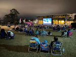 Free outdoor movies in Orlando: image of people sitting in lawn chairs watching a movie in the park in the city of Oviedo, Florida