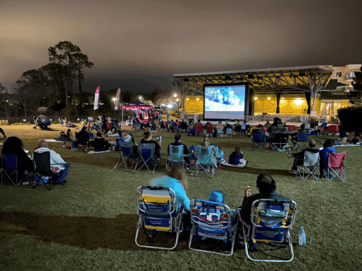 Free outdoor movies in Orlando: image of people sitting in lawn chairs watching a movie in the park in the city of Oviedo, Florida