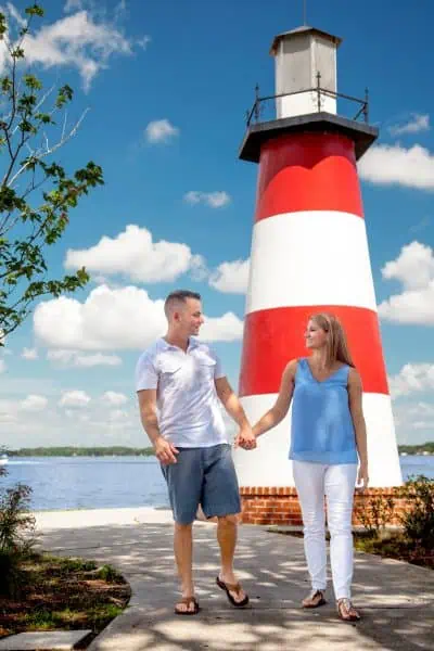 Date night ideas Orlando: image of a couple holding hands in front of the red and white lighthouse in Mount Dora, Florida