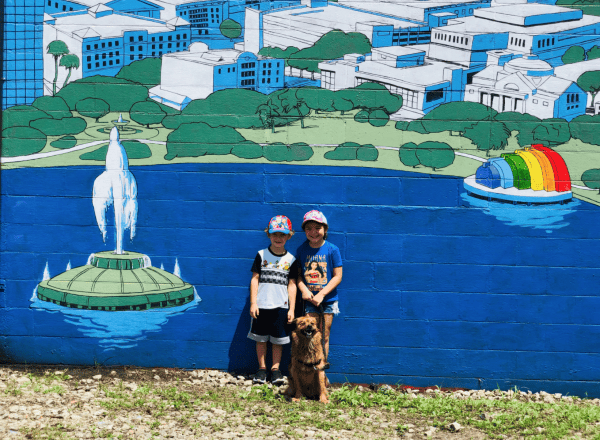 Best spots to take your dog in Orlando: image of two kids with their dog in front of a mural of Lake Eola Park in Orlando