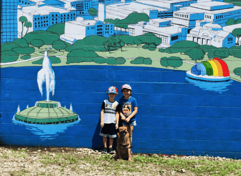 Best spots to take your dog in Orlando: image of two kids with their dog in front of a mural of Lake Eola Park in Orlando